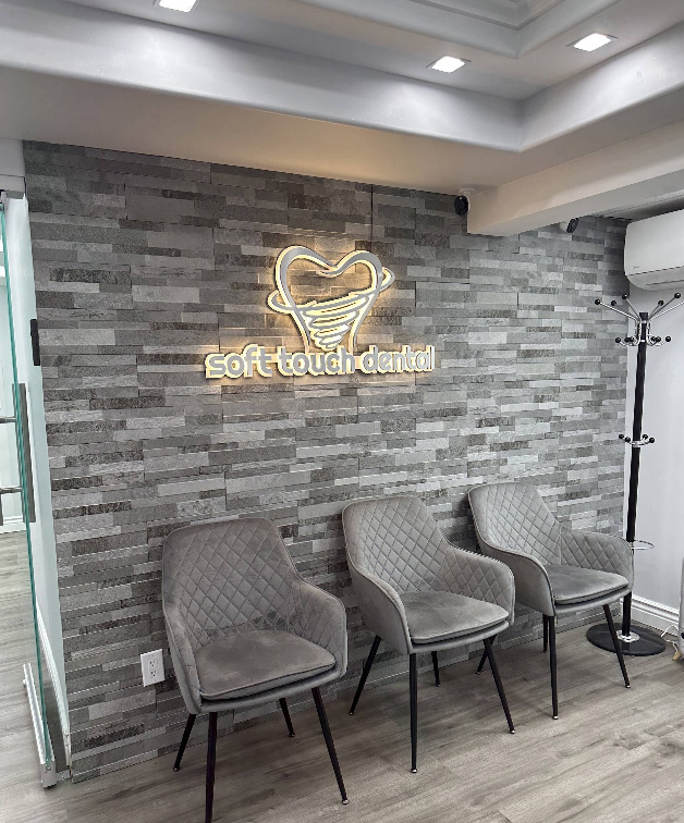 The image shows an interior space with a sign on the wall that reads  SOFT TOUCH DENTAL  accompanied by a neon light graphic of a tooth, and below it, there are chairs in front of a counter.