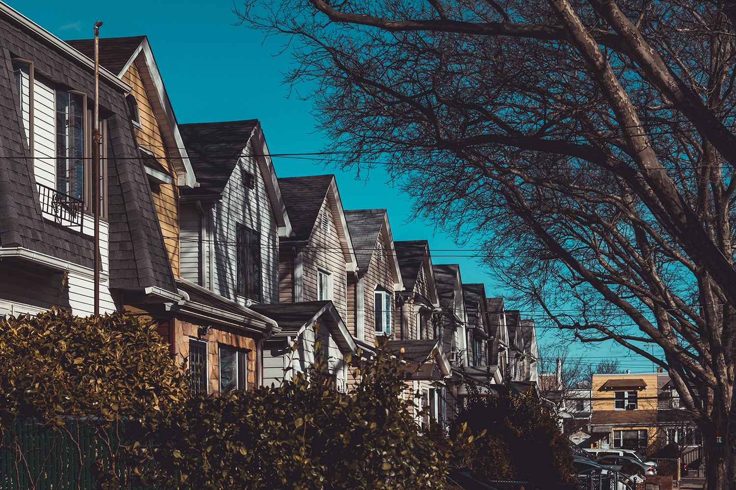 The image shows a row of residential houses with distinct architectural features, situated under a clear sky with no visible text or people.