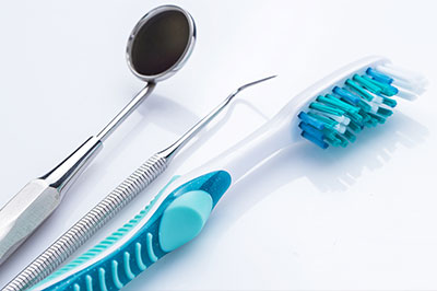 An assortment of dental instruments and toothbrushes displayed on a white background.