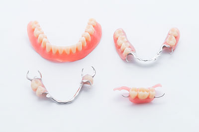 The image displays three pairs of dentures with visible teeth on a white background, presented in a way that suggests they are for sale or display.