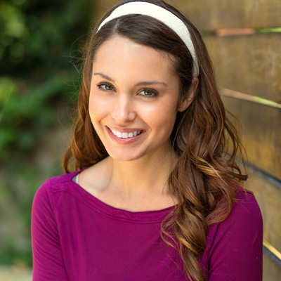 A young woman with long hair wearing a headband, smiling at the camera.