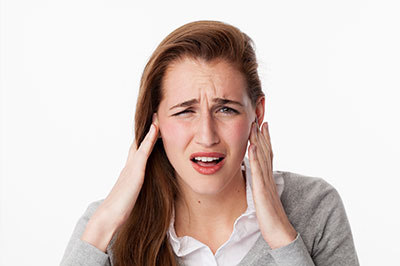 The image features a woman with her hand on her ear, appearing to be experiencing discomfort or pain, possibly due to an ear issue or injury.