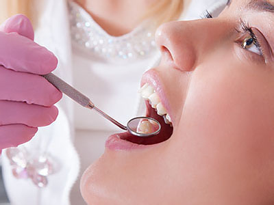A woman receiving dental care, with a dental professional using tools on her teeth.